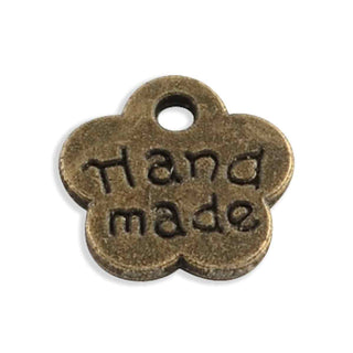 Dije Flor con Mensaje “Hecho a Mano” Tono Bronce Envejecido 8x8.5x1mm | 20 uds